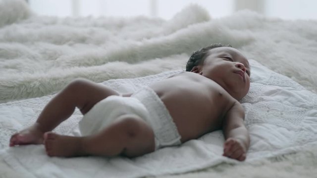 Newborn baby is lying alone on the bed.