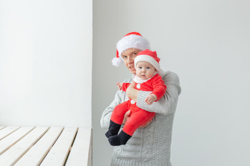 Fatherhood and holidays concept - Father with his baby boy wearing Santa hats celebrating Christmas
