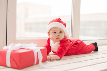 Beautiful little baby celebrates Christmas. New Year's holidays. Baby in a Christmas costume and in santa hat