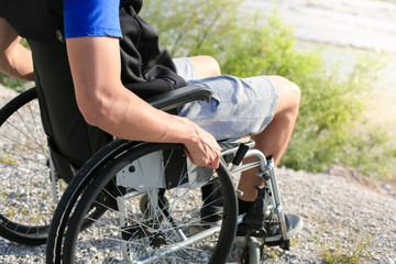 Obraz premium Happy young man in wheelchair outside in nature on a sunny summer day
