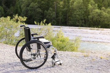 Empty wheelchair standing in a park on walking path