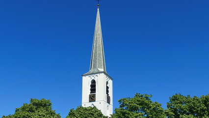 spitziger glockenturm, Kirchturm mit uhr ragt in den blauen himmel 