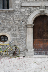 Detail of entrance of a medieval palace with stone wall and pillar with Doric capital and a bicycle leaning against the wall