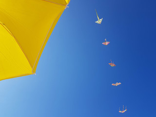 Detail of yellow umbrella and kites in the blue sky