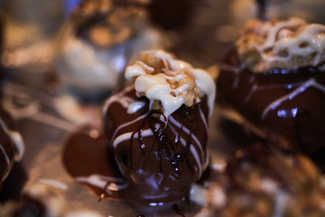 Makro close up of many isolated fresh homemade white and brown chocolate pralines filled with dates fruits, decorated with walnuts and  spread out on tray with Aluminium foil to dry