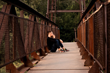 A young man on a bridge smokes a cigarette