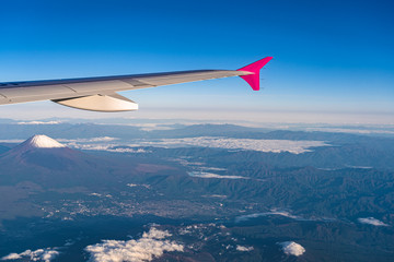 Naklejka na ściany i meble Aerial view of airplane wing with Mount Fuji ( Mt. Fuji ) in background and blue sky. Scenery landscapes of the Fuji-Hakone-Izu National Park. Gotemba city, Shizuoka Prefecture, Japan