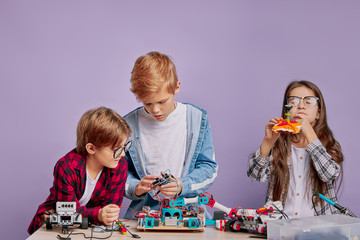 portrait of creative enthusiastic children spending time in engineering club, future engineers assembling robots. science, robotics concept