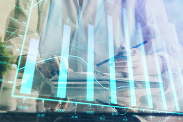 Financial forex graph drawn over hands taking notes background. Concept of research. Double exposure