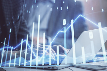 Double exposure of market chart with man working on computer on background. Concept of financial analysis.