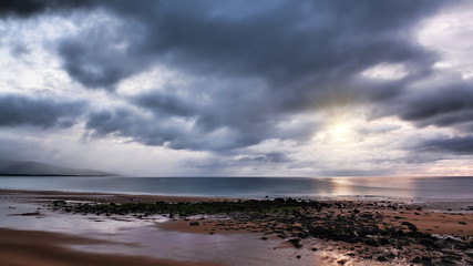 Heavy rain clouds and sunshine over Brora beach in the Highlands of Scotland on the North Coast 500