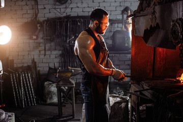 portrait of young male metalworker near furnace, young muscular in good physical form. strength, power concept