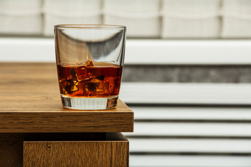 Whiskey with ice or brandy in a glass and a square carafe on an old wooden background. Whiskey with ice in a glass. Whiskey or cognac. Selective focus.