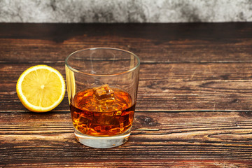 Whiskey with ice or brandy in a glass and a square carafe on an old wooden background. Whiskey with ice in a glass. Whiskey or cognac. Selective focus.
