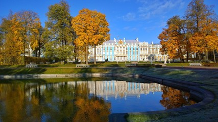 Fototapeta na wymiar Catherine Palace and Park in Pushkin, a suburb of St. Petersburg, Russia. A favorite place for excursions and travel of tourists. Reflection of green and orange trees in a pond. Colorful golden autumn