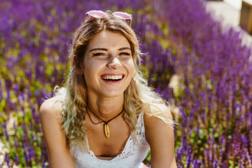 girl laughs while sitting in a park on a background of purple flowers