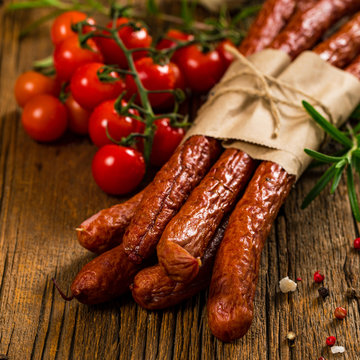 Kabanos or Cabanossi Thin Dry Smoked Polish Sausage on Wooden Background. Selective focus.
