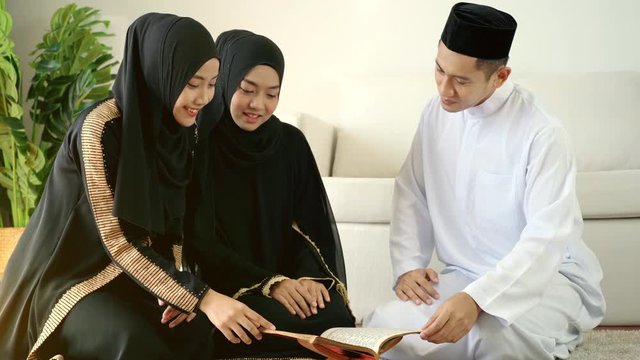 Portrait of an Asian Muslim family reciting surah al-Fatiha passage of the Qur'an, public item of all Muslims in a daily prayer at home in a single act of sujud called a sajdah or prostration