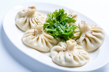 Georgian khinkali and a bunch of parsley on a plate. 