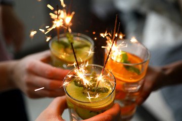 Young group friends hold in hand cocktail with sparkler