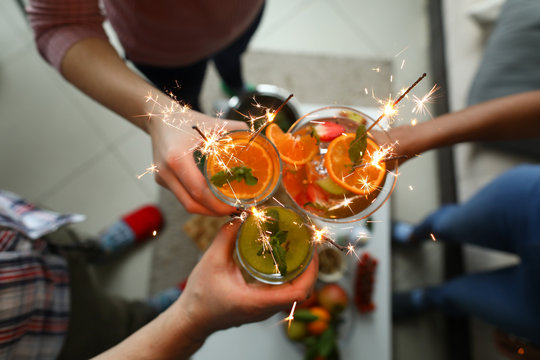 Young group friends hold in hand cocktail with sparkler