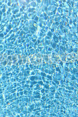 Fototapeta na wymiar Background of pool water texture. Reflection of sun rays in pool water. Vertical, close-up, cropped shot. Sports and recreation concept.
