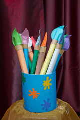 Round brush, flat brush and jar for painting . Made of paper brush in tin box in art room.