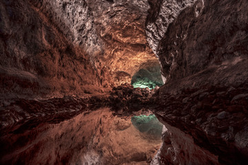 Cueva volcánica reflejada en lago espejo