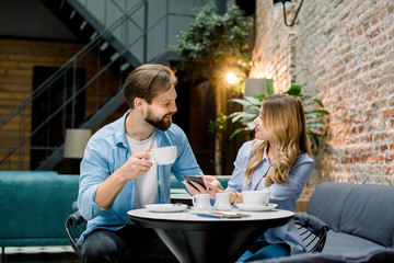 Happy couple or friends flirting talking and drinking coffe in a restaurant or cafe or waiting room