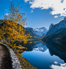 Peaceful autumn Alps mountain lake. Gosauseen or Vorderer Gosausee lake, Upper Austria. Dachstein summit and glacier in far.