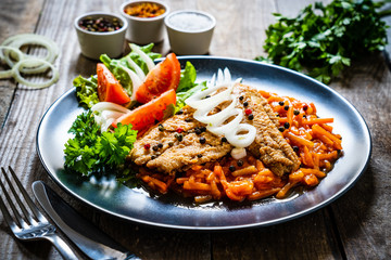 Fish dish - fried fish fillet on vegetable sauce on wooden table