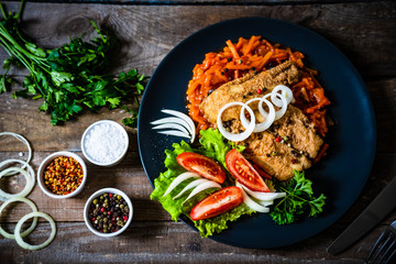 Fish dish - fried fish fillet on vegetable sauce on wooden table