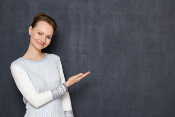 Portrait of happy optimistic girl pointing with hand at copy space