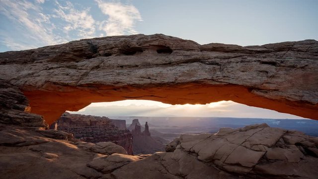 Timelapse at sunrise of Mesa Arch lighting up and glowing in the Utah desert of Canyonlands.