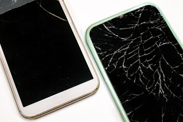 Smartphones with broken screens. Isolated on white background. Damaged mobile phones are in a diagonal pattern. The displays are shattered and taped. 