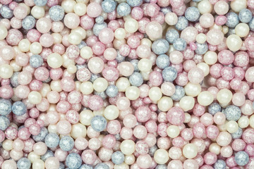 background of colorful sugar sprinkles in white, pink and blue