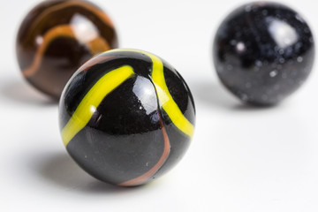 group of opaque glass marbles in black with yellow and orange - 308279194