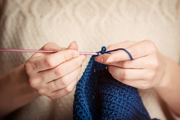 Young Woman in Sweater Knitting with Crochet Hook