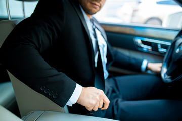 safety concept. cropped man in formal wear fastening safety belt before riding in car.