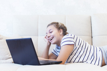 Fototapeta premium blonde girl is sitting at home on the couch with a laptop and communicates on the Internet. social networks. dating.