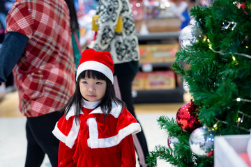 Portrait of cute asian little girl wear santa dress happy near christmas tree,Thailand kid join christmas festival