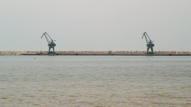 Symetric wide shot of ship cranes standing at the rocky sea coast in Croatia summertime daylight.