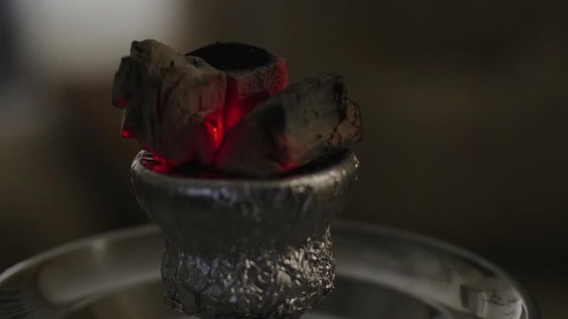 Hot ember on a hookah set lights up turning red when vaping.
