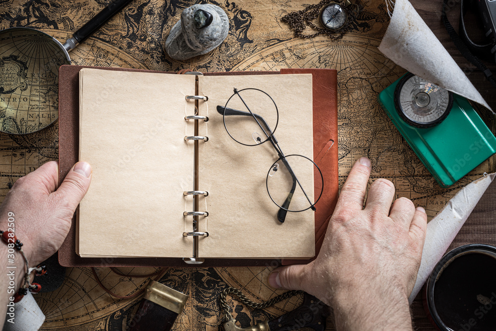 Fototapete Travel planning. A finger roaming the map. An open notebook with space for text. Things useful in the expedition. Retro styl