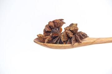 Chinese star anise in the wooden spoon isolated on a white background.