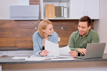 husband discussing contract details of financial issues with smiling happy wife. Married couple sit with paper document, making decision about house purchase, mortgage or financial investment.
