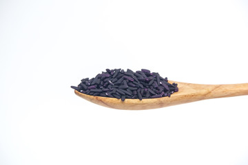 Black rice grain in the wooden spoon isolated on a white background.