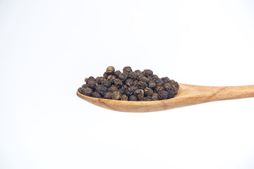 Black pepperBlack pepper in the wooden spoon isolated on a white background.