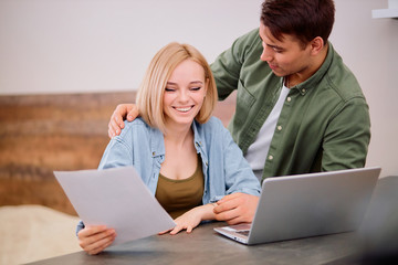 married couple thinking about future together at home, using laptop and checking documents, dream about new house