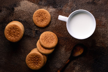 Fresh milk with homemade cookies on a wooden table, dark background.